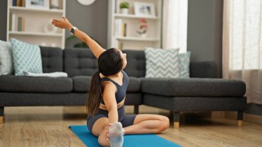 Genç, güzel İspanyol bir kadın. Bacağını esnetiyor. Evinde yerde oturuyor.