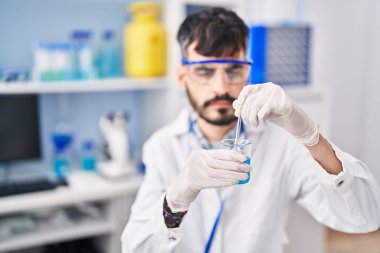 Genç İspanyol bilim adamı laboratuvarda cama sıvı karıştırıyor.