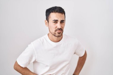Beyaz arka planda, hazımsızlık ve acı veren hastalıklardan dolayı elleri karnında duran yakışıklı İspanyol bir adam. Ağrı kavramı. 