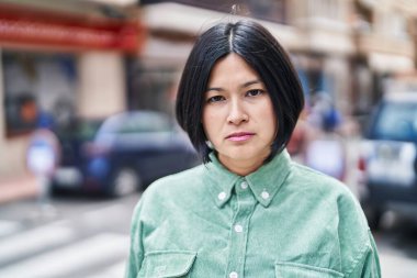Young chinese woman with relaxed expression standing at street