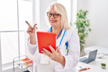 Orta yaşlı, beyaz bir kadın online randevuda çalışıyor. Gülümsüyor, mutlu bir şekilde işaret ediyor. 