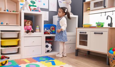 Adorable hispanic girl standing with relaxed expression at kindergarten