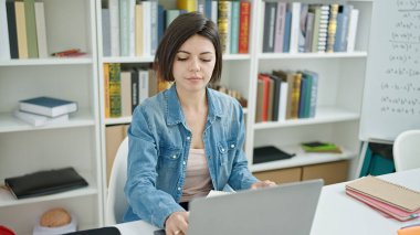 Üniversite sınıfında dizüstü bilgisayar kullanan beyaz bir kız öğrenci.