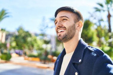 Genç İspanyol adam gülümsüyor parkın kenarına bakıyor.