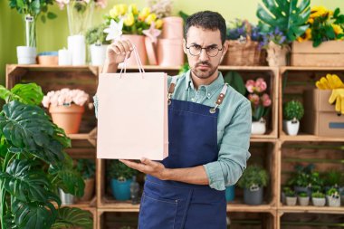 Handsome hispanic man working at florist shop skeptic and nervous, frowning upset because of problem. negative person. 