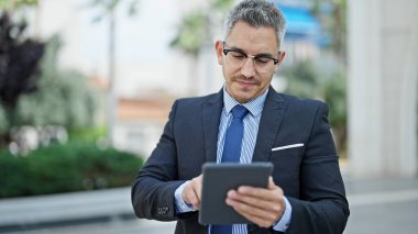 Sokakta dokunmatik ped kullanan İspanyol bir iş adamı.