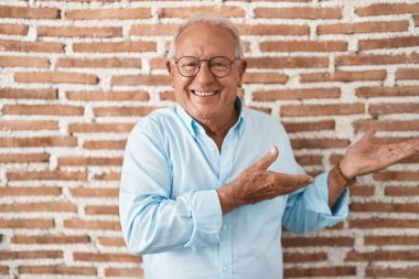 Tuğla duvarın üzerinde duran yaşlı adam gülümseyerek içeri girmeye davet ediyor. 