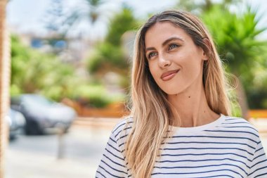 Young blonde woman smiling confident looking to the side at street