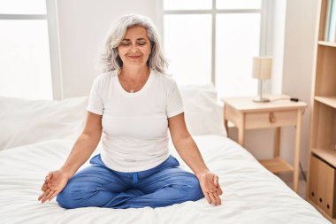 Orta yaşlı bir kadın yatak odasında yoga egzersizi yapıyor.