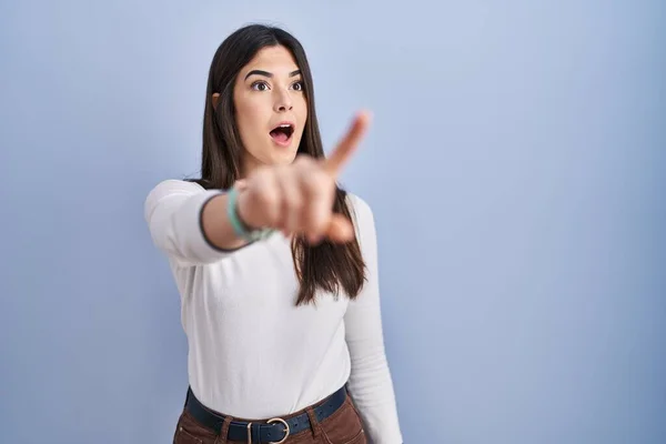 Genç Esmer Kadın Mavi Arka Planda Dikiliyor Parmağıyla Işaret Ediyor — Stok fotoğraf