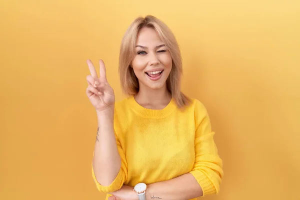Sarı Kazak Giyen Gülümseyen Kameraya Göz Kırpan Beyaz Bir Kadın — Stok fotoğraf