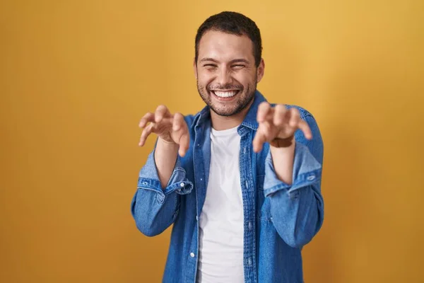 Hispanic Man Standing Yellow Background Smiling Funny Doing Claw Gesture — ストック写真