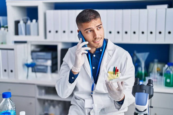 Young Hispanic Man Scientist Talking Smartphone Laboratory — Foto de Stock