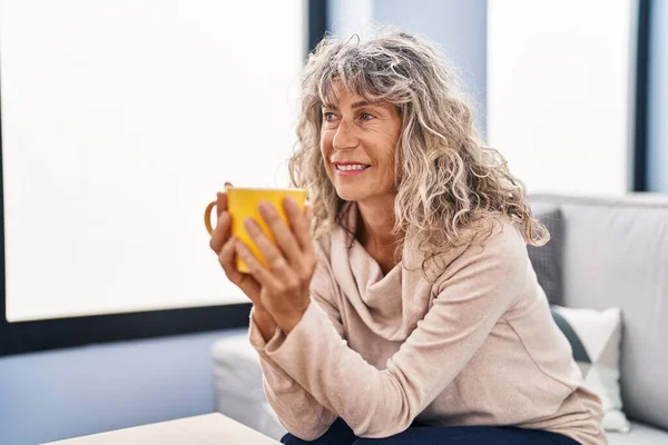 Kobieta Średnim Wieku Pije Kawę Siedząc Kanapie Domu — Zdjęcie stockowe