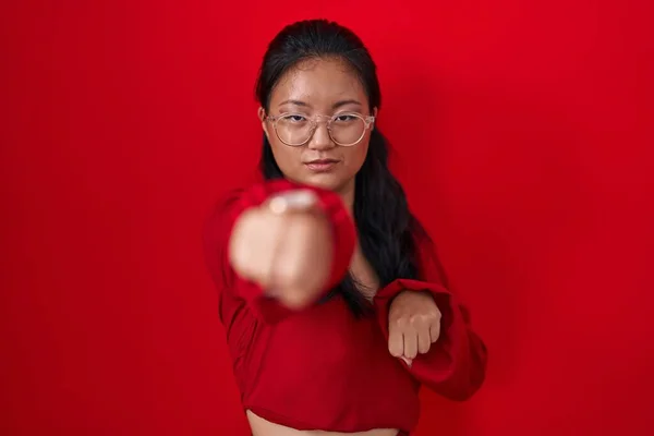 Azji Młoda Kobieta Stojąca Czerwonym Tle Uderzając Pięść Walki Agresywny — Zdjęcie stockowe