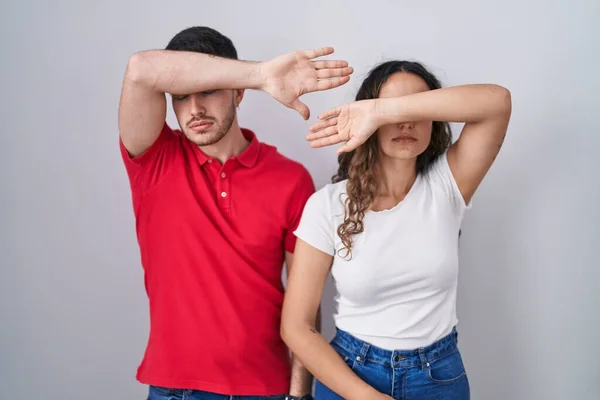 Young Hispanic Couple Standing Isolated Background Covering Eyes Arm Looking — Stock Photo, Image