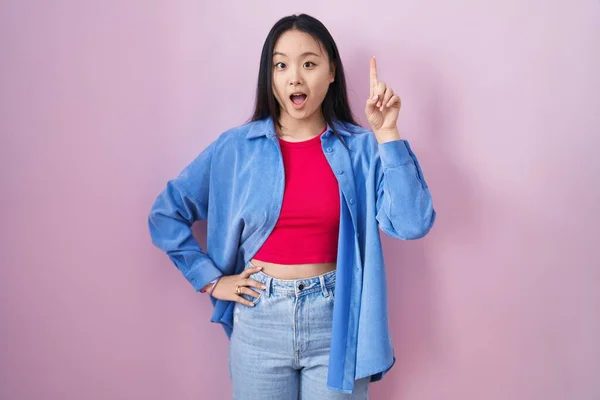Young Asian Woman Standing Pink Background Pointing Finger Successful Idea — Zdjęcie stockowe