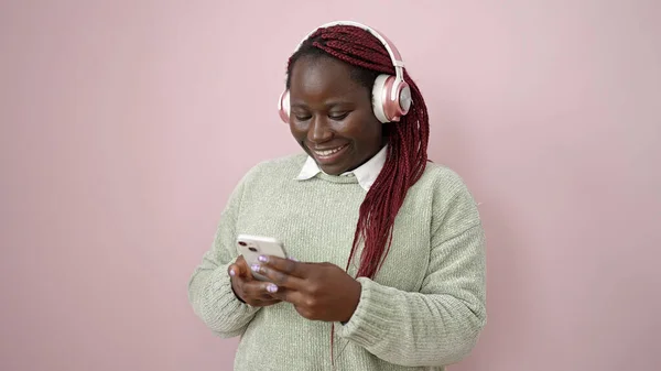 Африканская Женщина Плетеными Волосами Помощью Смартфона Наушниках Изолированном Розовом Фоне — стоковое фото