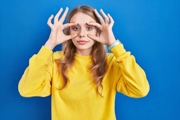 Young Caucasian Woman Standing Blue Background Trying Open Eyes Fingers — Stock fotografie