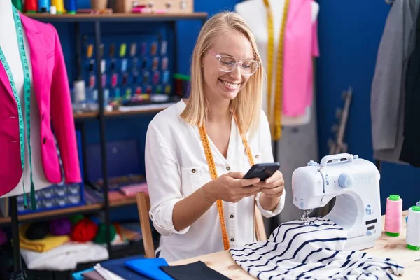 Young Blonde Woman Tailor Smiling Confident Using Smartphone Sewing Studio — Stock Fotó