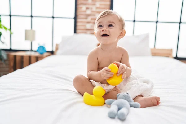 可爱的高加索男孩抱着鸭玩具坐在卧室的床上 — 图库照片