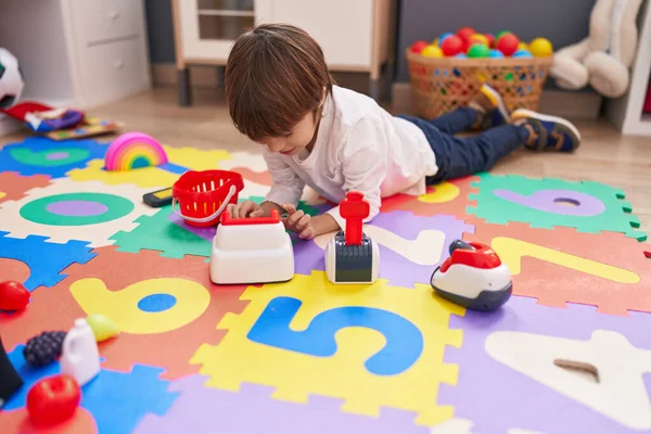 stock image Adorable caucasian boy playing with supermarket toy lying on floor at kindergarten