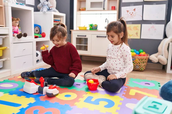 Anaokulunda yerde oturmuş süpermarket oyunu oynayan güzel kızlar.