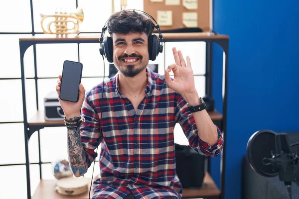 Jonge Spaanse Man Met Baard Tonen Smartphone Scherm Muziekstudio Doet — Stockfoto