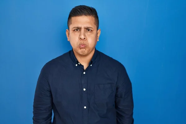 Hispanic Young Man Standing Blue Background Puffing Cheeks Funny Face — Stock Fotó