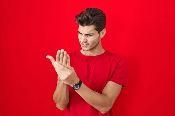 年轻的惊慌失措的男人站在红底上 手指头疼痛 关节炎发炎 — 图库照片