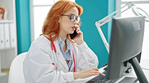 Young Redhead Woman Doctor Using Computer Talking Smartphone Clinic — Stock Photo, Image