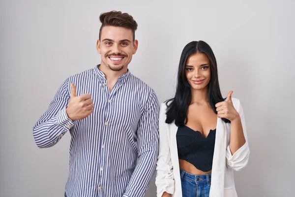 Unga Latinamerikanska Par Står Över Vit Bakgrund Gör Glada Tummen — Stockfoto