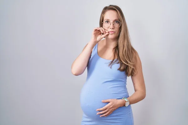 白い背景の口と唇の上に立つ若い妊婦は指でZipとしてシャットダウンします 秘密裏に黙ってタブーを語る — ストック写真