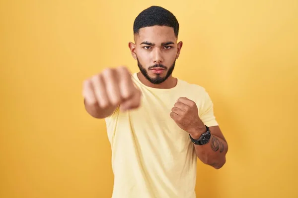 Young Hispanic Man Standing Yellow Background Punching Fist Fight Aggressive — Stockfoto