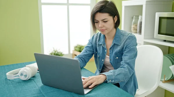 年轻的高加索女人坐在家里的桌子上 用笔记本电脑 — 图库照片