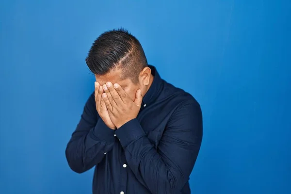 Jovem Hispânico Sobre Fundo Azul Com Expressão Triste Cobrindo Rosto — Fotografia de Stock