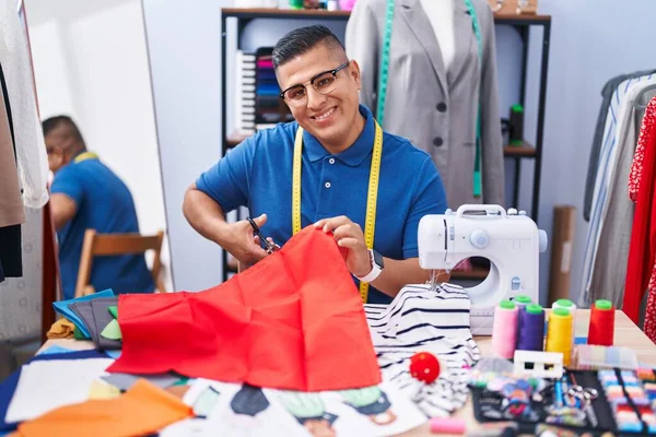年轻的拉丁男人裁缝店裁缝师自信地微笑着裁剪布料 — 图库照片