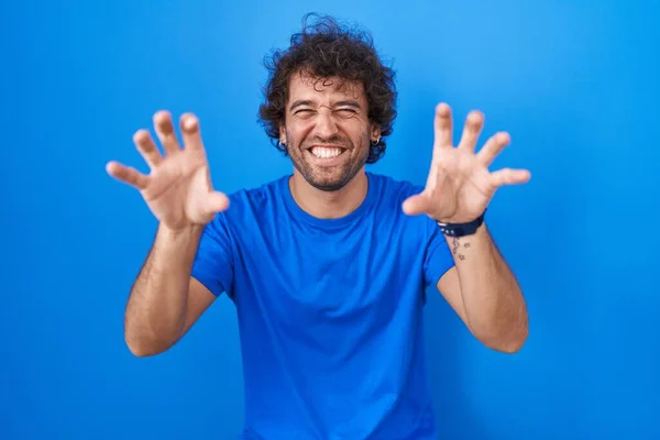 Jovem Hispânico Sobre Fundo Azul Sorrindo Engraçado Fazendo Gesto Garra — Fotografia de Stock