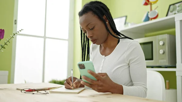 African American Woman Using Smartphone Writing Notebook Home — Photo