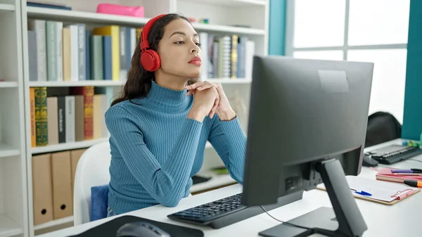 若い美しいですヒスパニック女性学生使用コンピュータを身に着けていますヘッドフォンで大学教室 — ストック写真