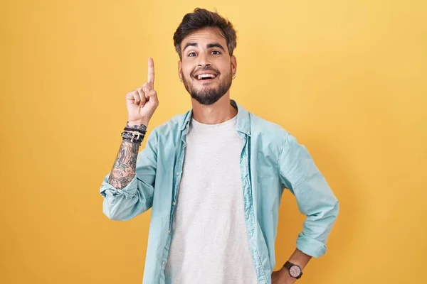 Sarı Arka Planda Dikilen Dövmeleri Olan Spanyol Genç Adam Başarılı — Stok fotoğraf