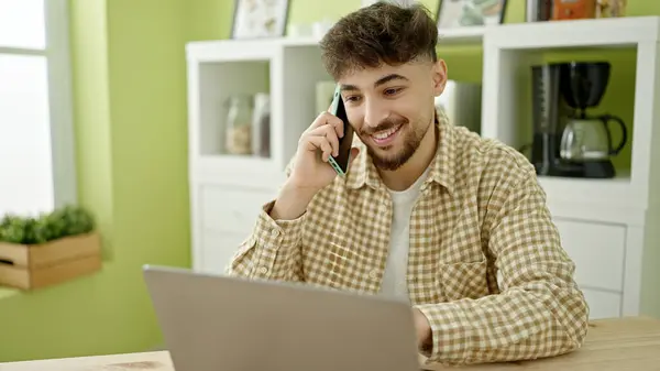 Hombre Árabe Joven Usando Ordenador Portátil Hablando Teléfono Inteligente Casa —  Fotos de Stock