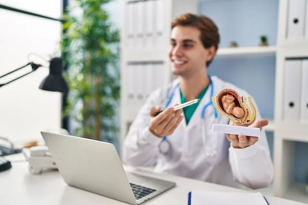 若いですCaucasian男医師保持解剖モデルの子宮とともに胎児で話すクリニック — ストック写真