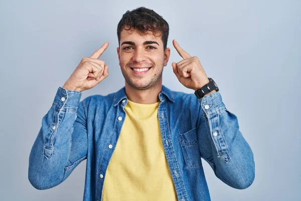 Homem Hispânico Jovem Sobre Fundo Azul Sorrindo Apontando Para Cabeça — Fotografia de Stock