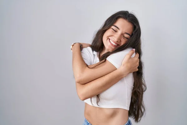 Młoda Nastolatka Stojąca Nad Białym Tłem Przytulająca Się Szczęśliwa Pozytywna — Zdjęcie stockowe