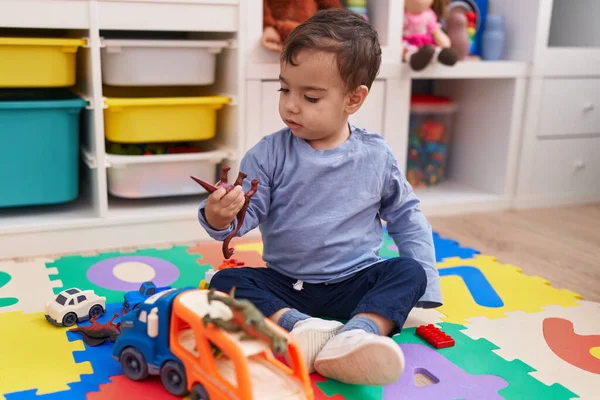 可爱的他的惊慌失措的男孩在幼儿园的地板上玩汽车和恐龙玩具 — 图库照片