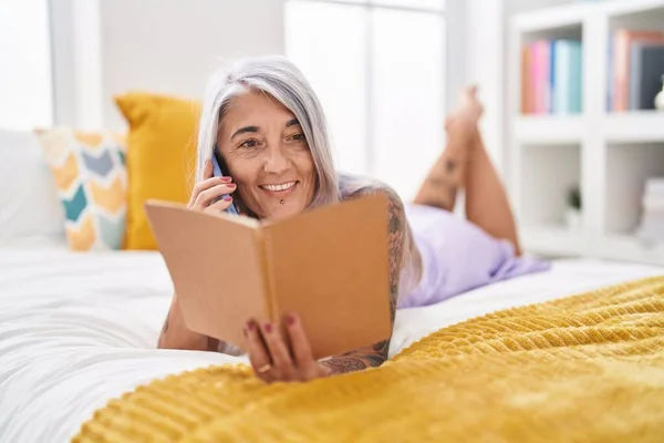 Middle Age Grey Haired Woman Talking Smartphone Reading Book Bedroom — Foto de Stock