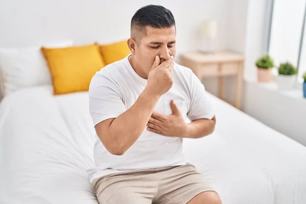 stock image Young latin man sitting on bed yawning at bedroom