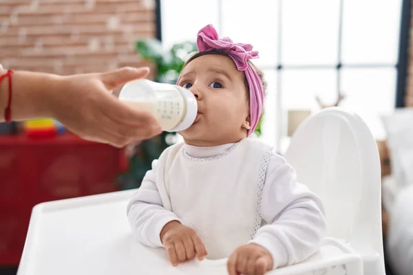 Nuttet Spansktalende Baby Spiser Mælk Fodring Flaske Sidder Højstol Derhjemme - Stock-foto
