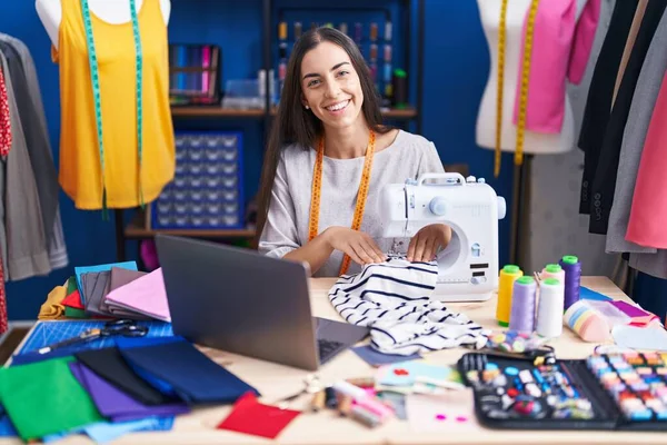 服装厂用缝纫机和笔记本电脑裁缝店的年轻漂亮女裁缝 — 图库照片